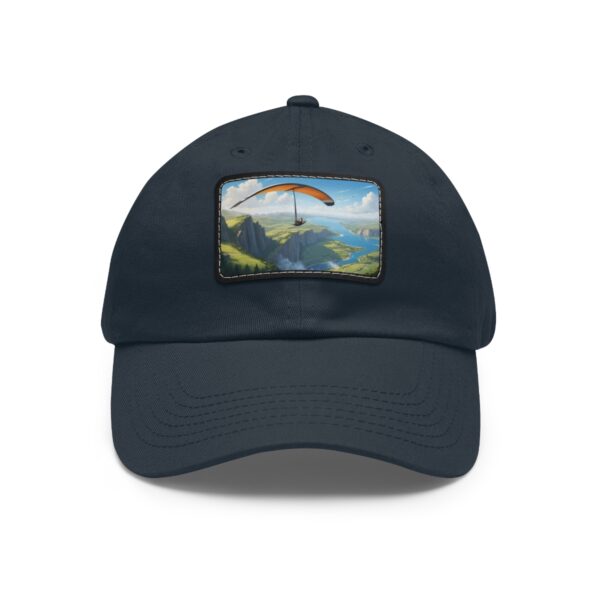 Dad Hat with rectangular patch featuring a paraglider soaring over a lush coastal mountain landscape