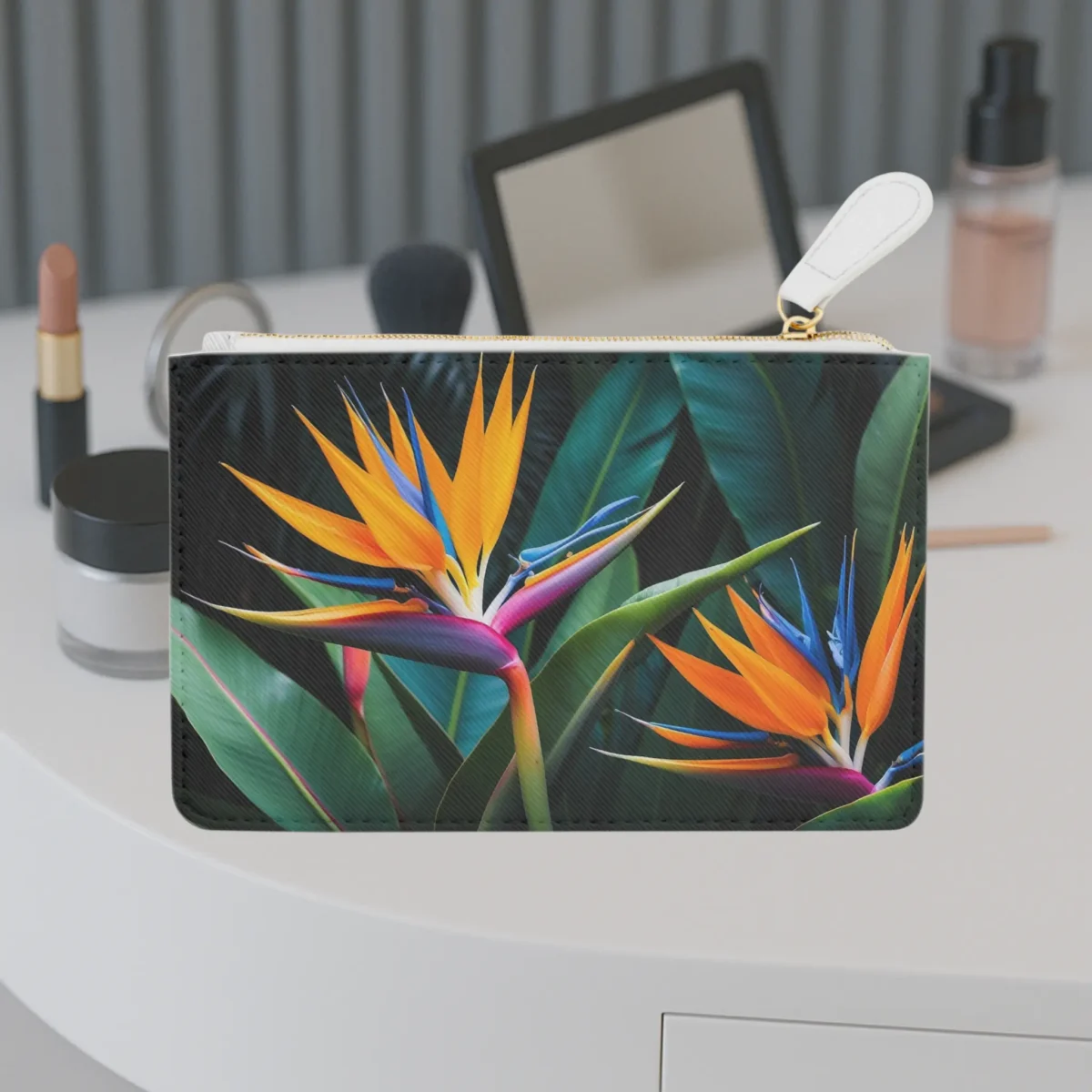 Mini clutch bag with a vivid bird of paradise flower design placed on a vanity table.