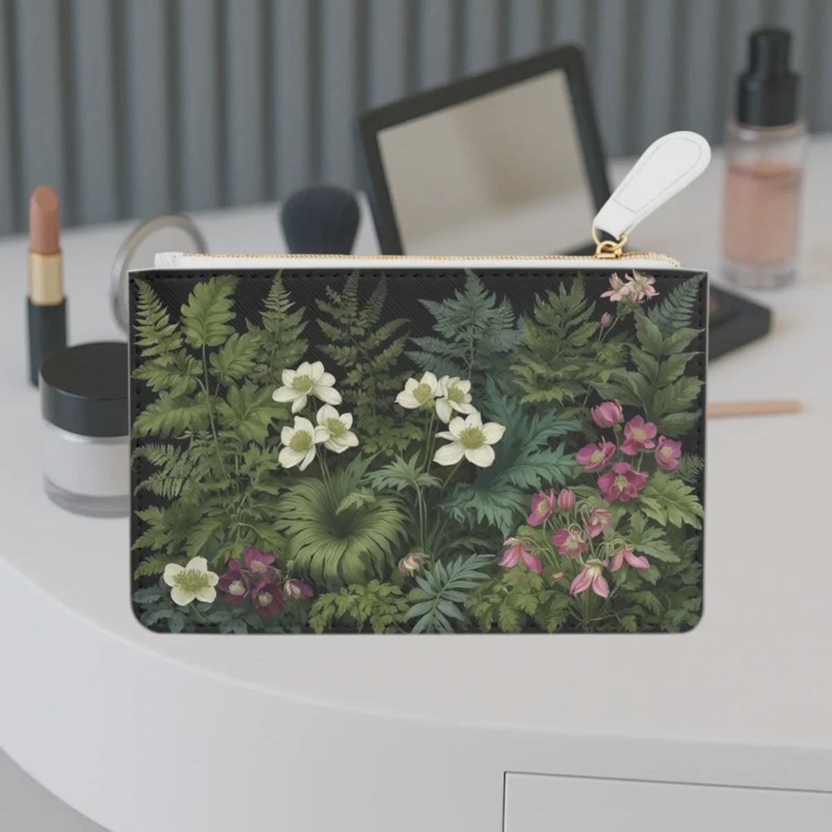 Mini clutch bag with a rich botanical design featuring green ferns and flowers on a vanity table.