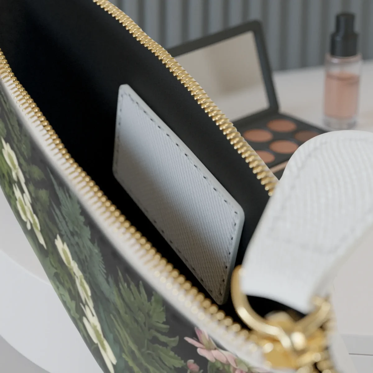 Close-up of the inside of the mini clutch bag showing the pocket and a portion of the botanical print.