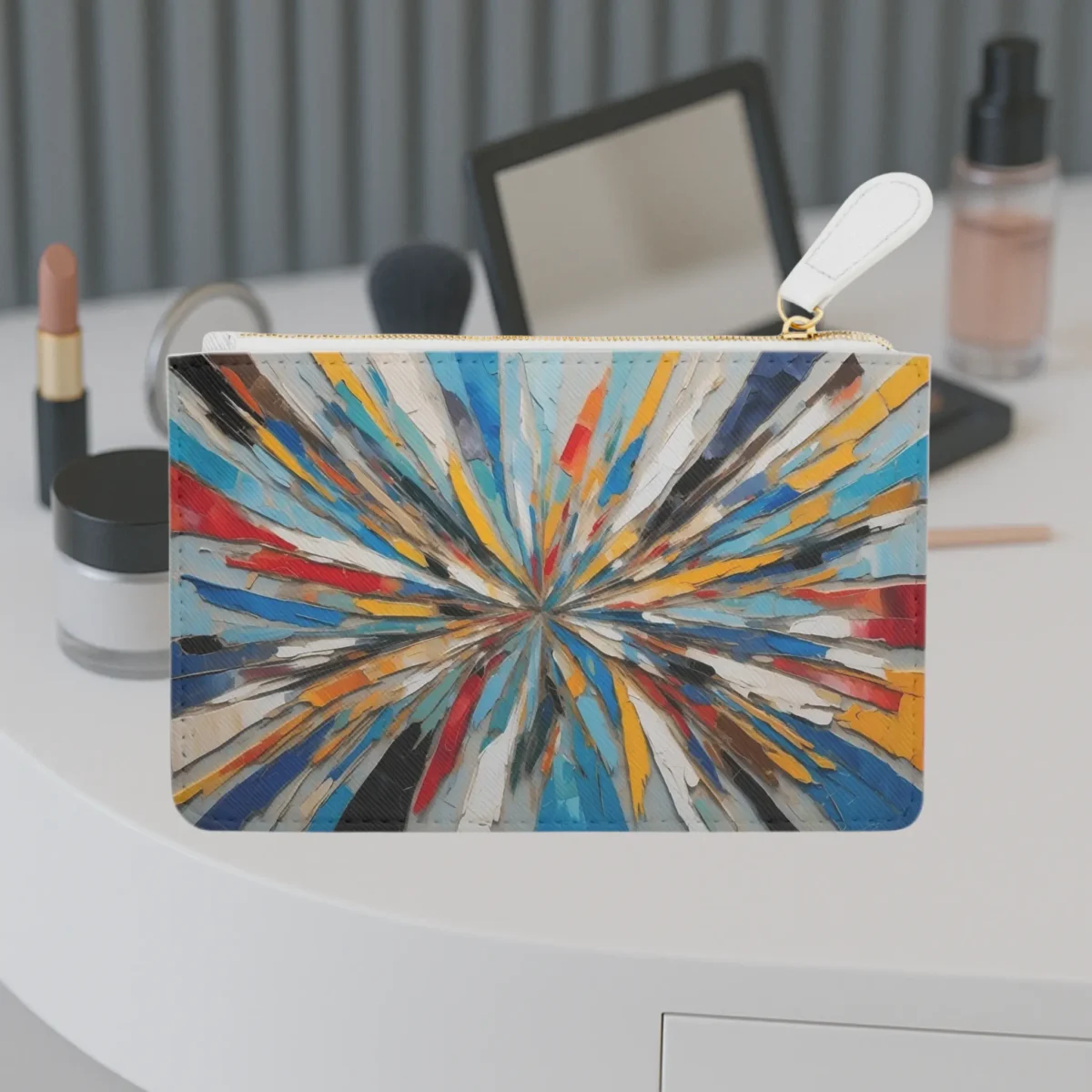 Mini clutch bag with a colorful explosion of abstract brushstrokes in a radial pattern, displayed on a vanity table.