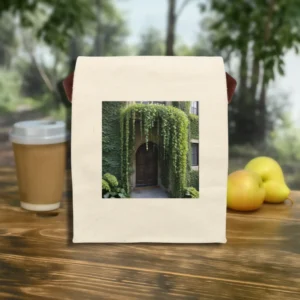 Reusable canvas lunch bag with “Archway Vines” print lying flat, surrounded by a coffee cup and apples outdoors.