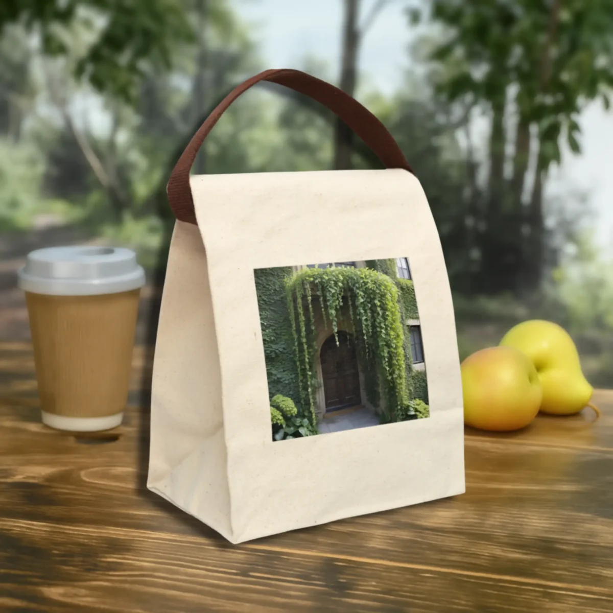 Eco-friendly canvas lunch bag with a nature-themed “Archway Vines” print and brown strap on a wooden table.