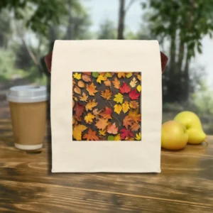 Flat front view of canvas lunch bag with a vibrant autumn leaves photo print, surrounded by apples and a takeaway coffee.