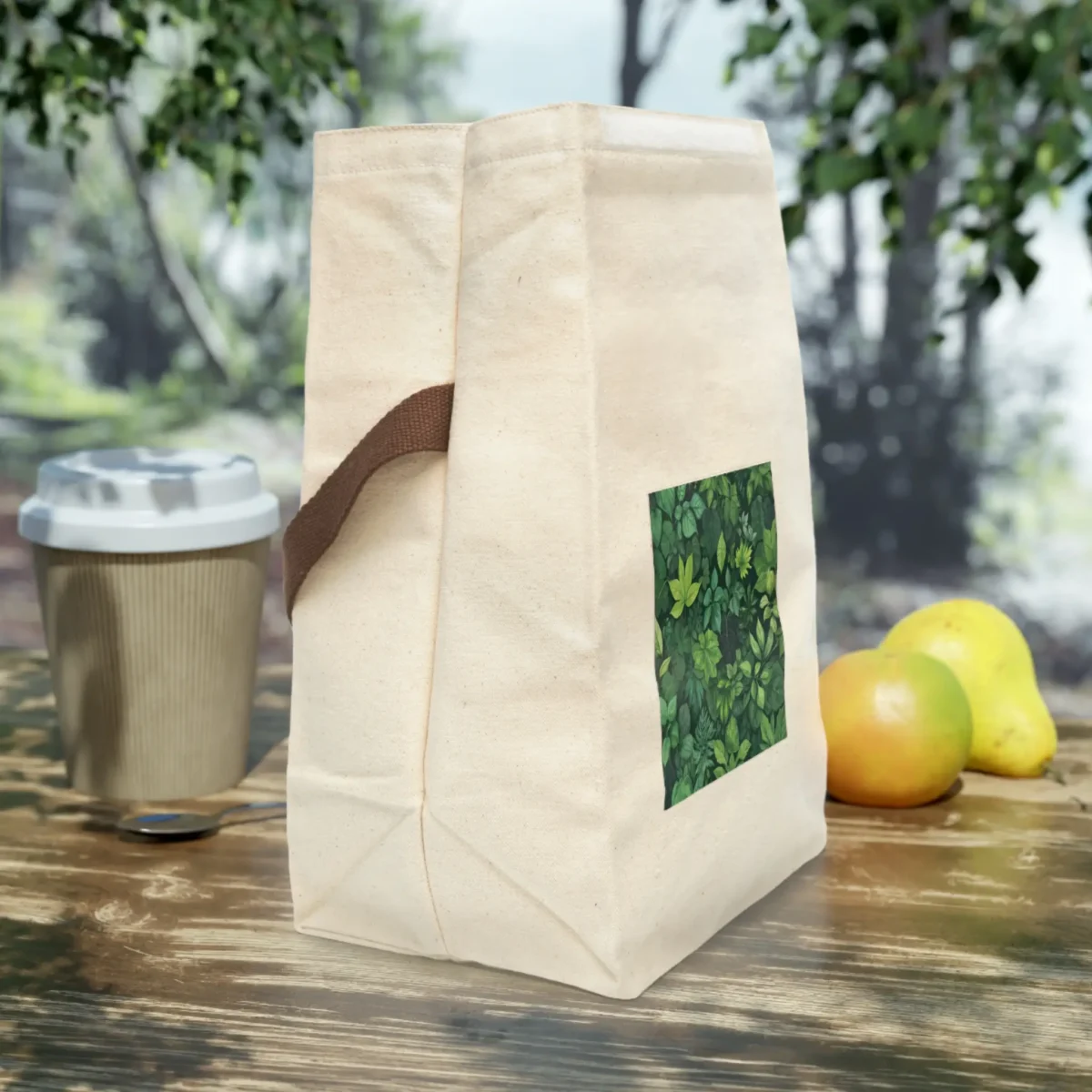 Side view of canvas lunch bag with green foliage design and brown strap.