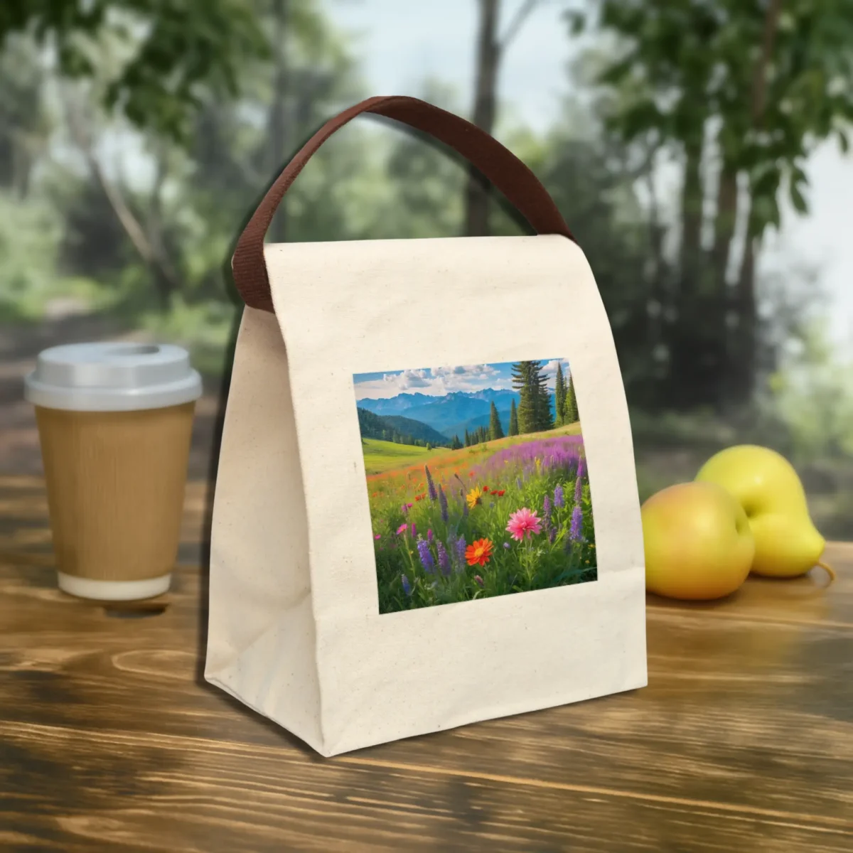 Canvas lunch bag with strap and mountain wildflower meadow design, placed outdoors on a table.