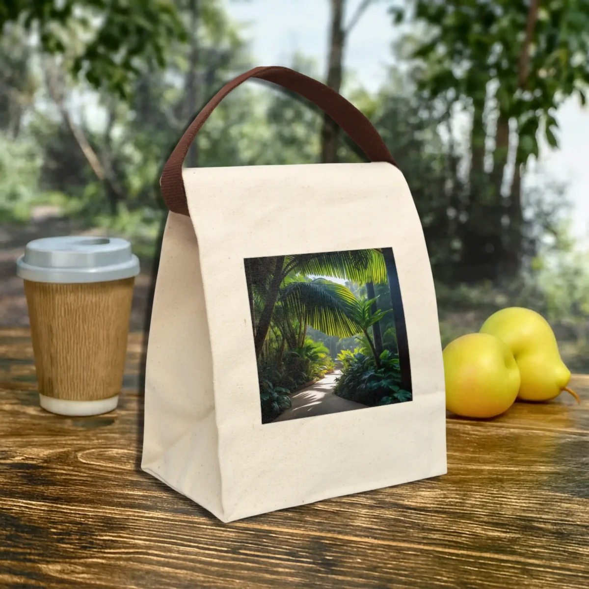 Canvas lunch bag with a print of a tropical jungle path, placed on a rustic wooden table outdoors.