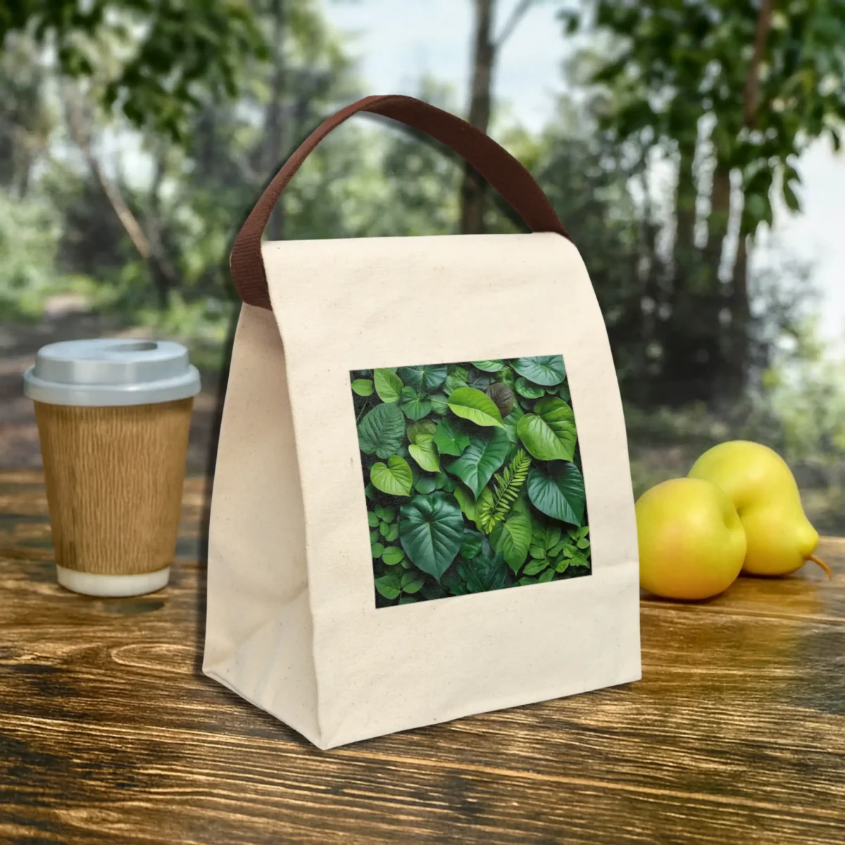 Reusable canvas lunch bag with brown handle and tropical leaves print displayed at an angle