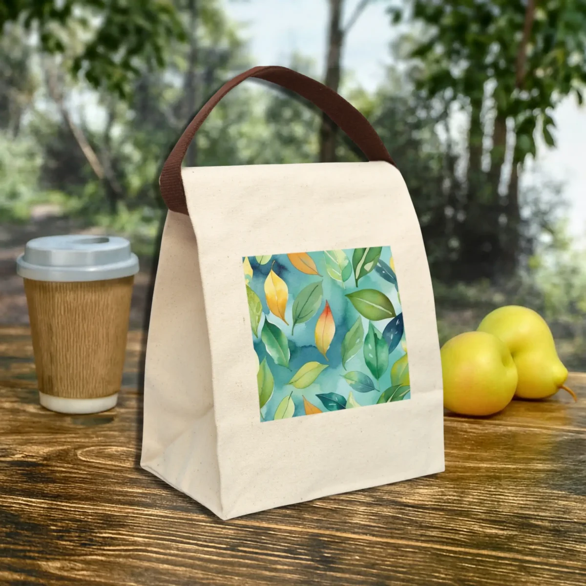Angled view of a canvas lunch bag with watercolor leaves design on natural fabric