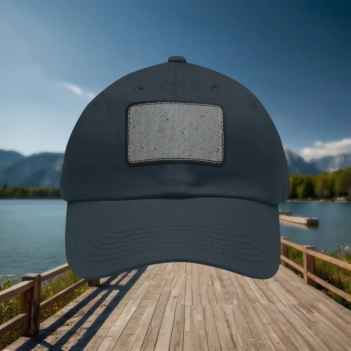 Navy blue dad hat with concrete texture patch design, displayed against a scenic lake and mountain backdrop.