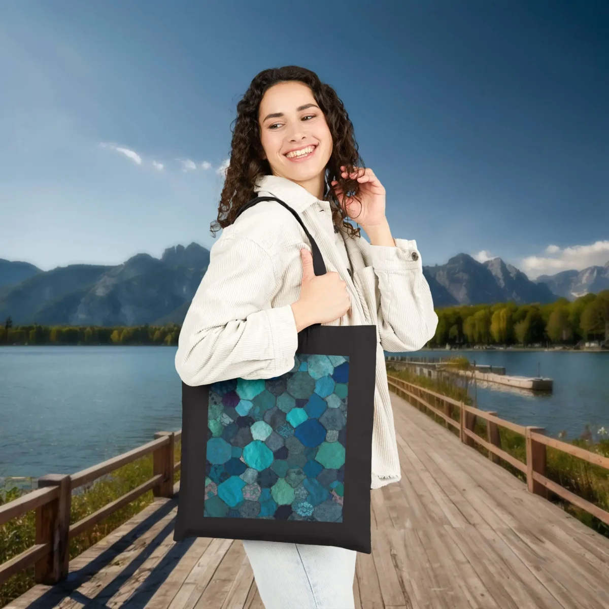 This black tote bag features a striking mosaic of hexagonal shapes in various shades of green, teal, and blue. The backdrop of serene lake and mountains enhances the modern, nature-inspired design. Ideal for those who appreciate style and practicality.