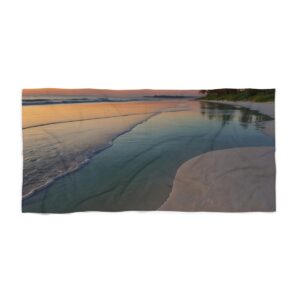 Tranquil beach at sunset with calm waves and soft sand beach towel