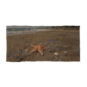 Beach towel with starfish and rocks on sandy shore near ocean waves