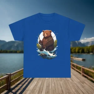 Royal blue t-shirt with a fun bear fishing illustration, displayed on a dock near a peaceful lake and mountain view.