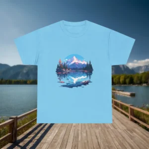 Flat lay of a light blue t-shirt with a scenic mountain and lake reflection design, displayed on a lakeside boardwalk.
