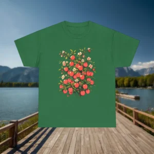 Flatlay of green t-shirt with red apple tree and white blossoms, placed on a dock