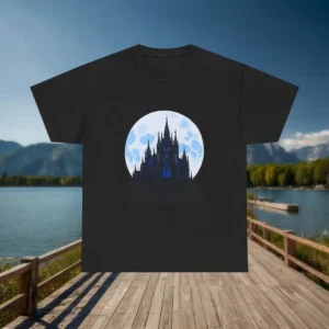Flatlay of a black t-shirt with gothic cathedral and moon design, displayed on a wooden bridge with a lake background