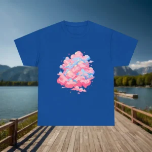 Blue t-shirt with colorful pink cloud artwork displayed flat on a boardwalk background by a mountain lake.