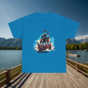 Flatlay of a blue t-shirt with a colorful pirate ship design, shown in front of a scenic lake and mountains.