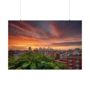 City skyline at sunset with vibrant orange and red clouds, overlooking a rooftop garden with lush green plants.