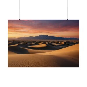 Expansive desert landscape with smooth sand dunes at sunset, casting long shadows under a vibrant sky with mountains in the background.