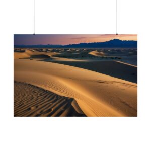 Rolling sand dunes in a desert illuminated by soft golden light at dusk, with distant mountains and a fading sky.