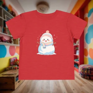 Flat lay of a red heather toddler t-shirt with a cute snowman illustration wearing a pink hat and scarf.