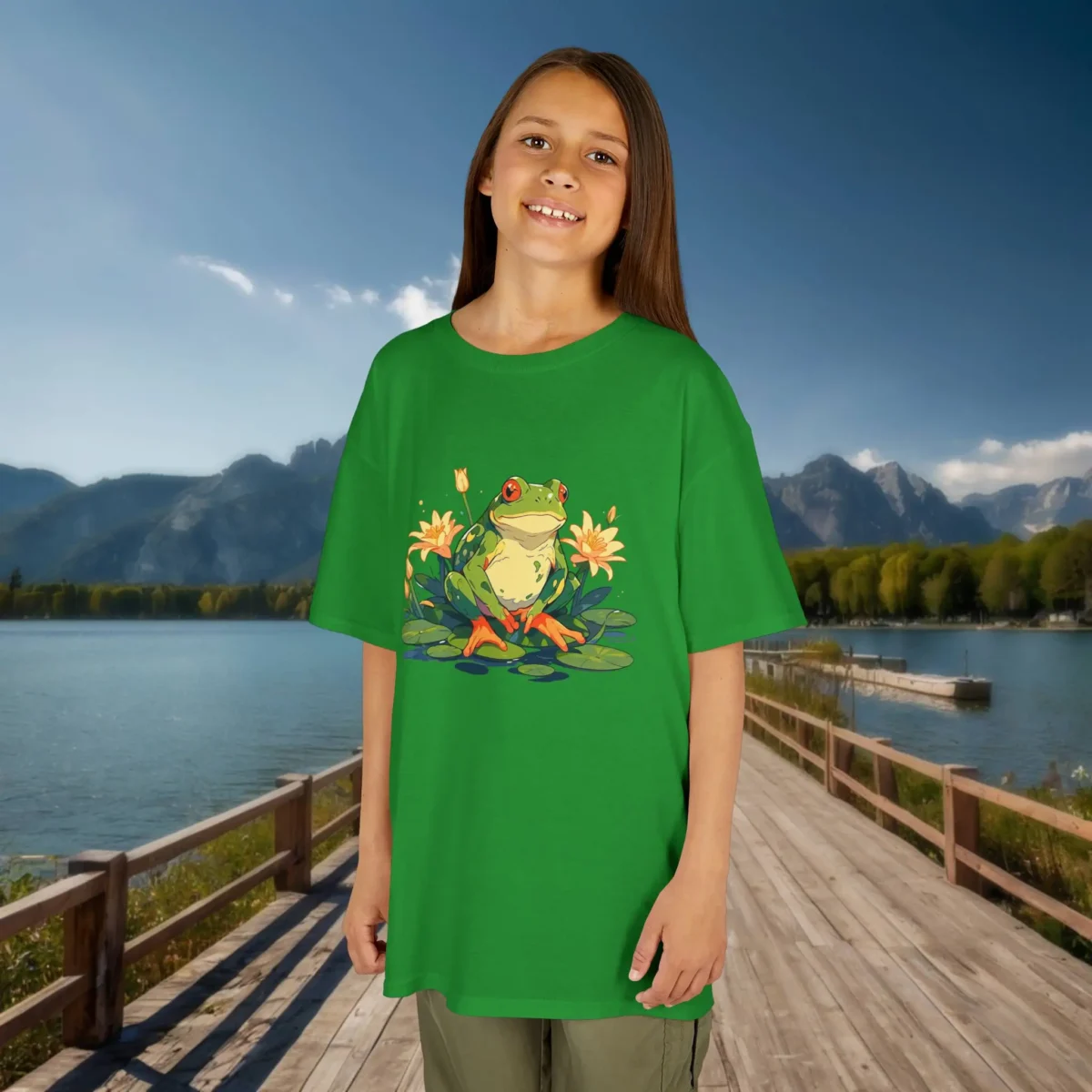 Girl wearing an Irish green t-shirt with a cute cartoon frog and yellow flowers on lily pads, standing on a wooden dock beside a lake.