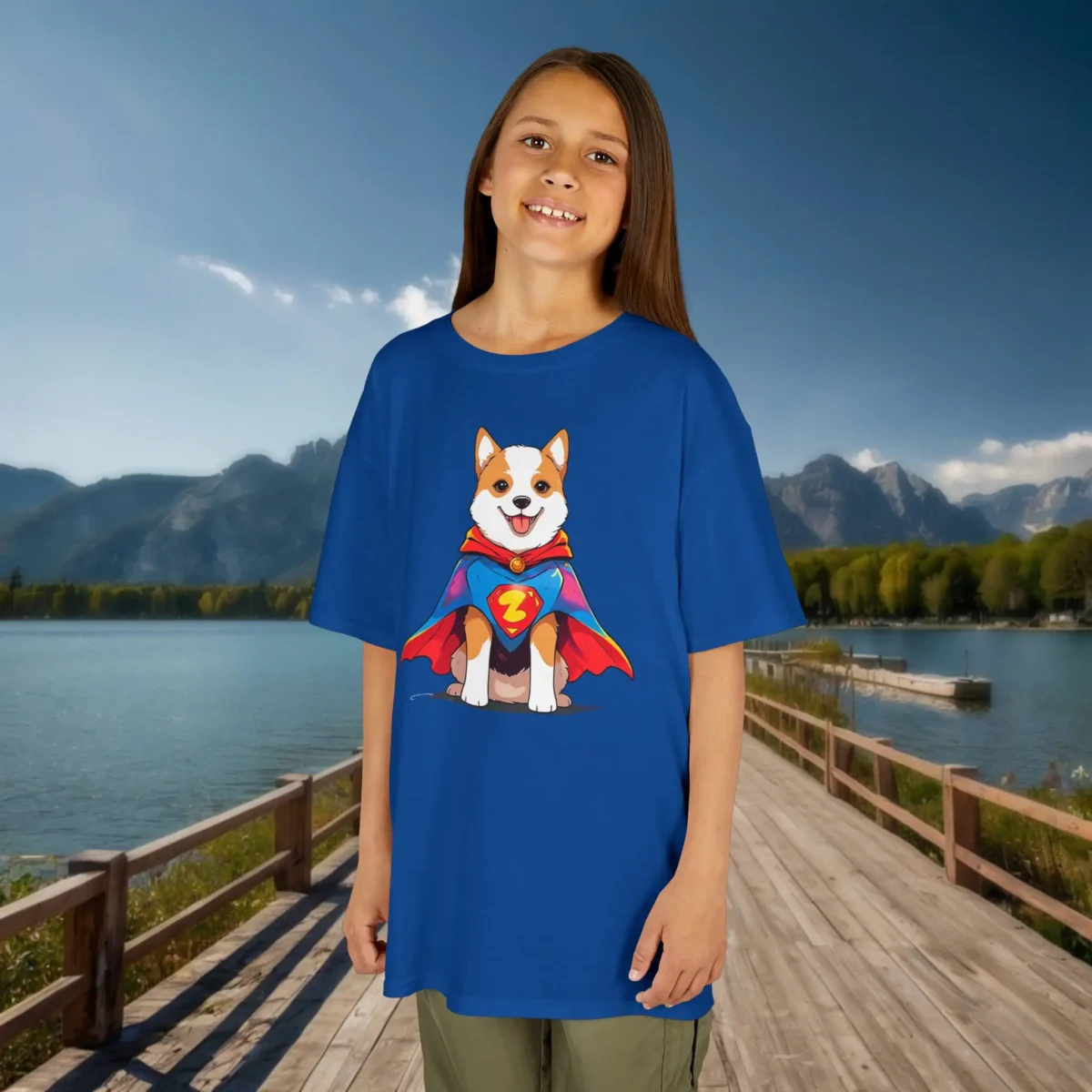 Girl wearing a royal blue kids t-shirt featuring a cartoon superhero dog with a red and blue cape and lightning bolt emblem.