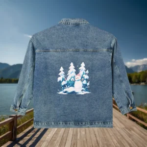Flat view of a denim jacket with a graphic of a snowman in a snowy pine forest.