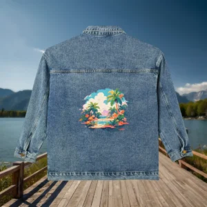 Flat view of a denim jacket with a colorful tropical island design printed on the back, photographed with a natural lake and mountain background.