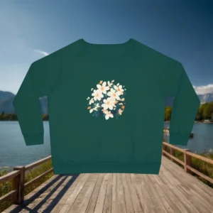 Flat lay of green women’s sweatshirt with jasmine floral design, displayed on boardwalk by the lake