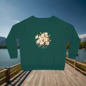 Flat lay of green women’s sweatshirt with a delicate lily bouquet floral print, displayed on a lakeside wooden walkway