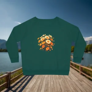 Flat lay of green sweatshirt with marigold floral design, displayed on a lakeside boardwalk