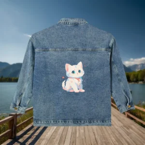 Flat lay of a denim jacket with a cute white kitten illustration on the back.
