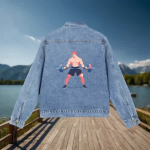 Flat view of a denim jacket with a bold illustration of a muscular man lifting a barbell on the back, placed on a dock by a lake.