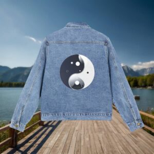 Flat-lay of a denim jacket with a Yin and Yang symbol design on the back, displayed on a wooden dock with a scenic mountain background.