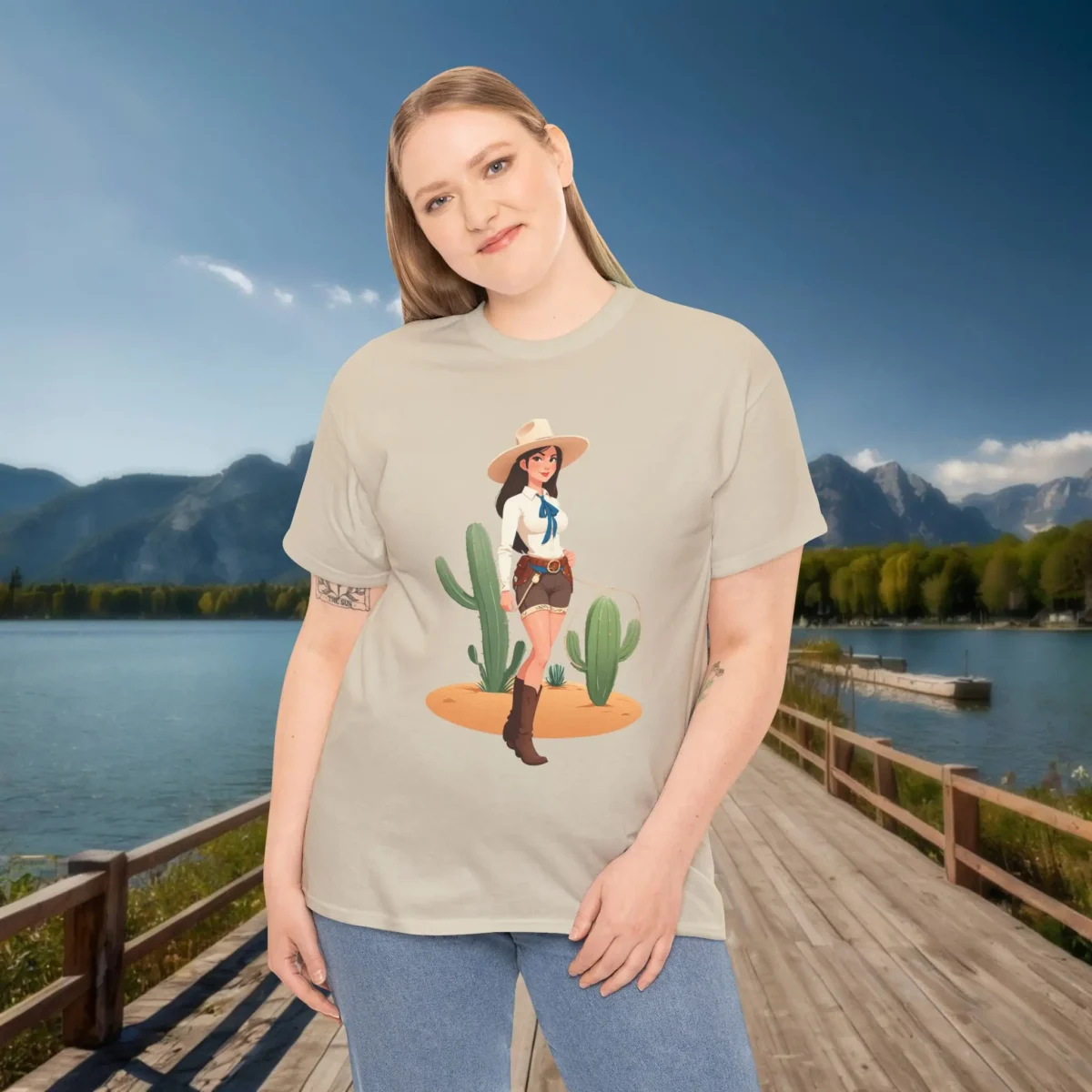 Woman wearing a beige t-shirt with a cartoon cowgirl design in front of cacti.