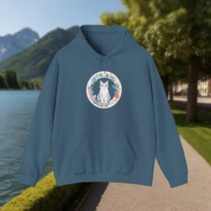 Blue hoodie with a cute cat and floral wreath graphic, shown by a lakeside path.