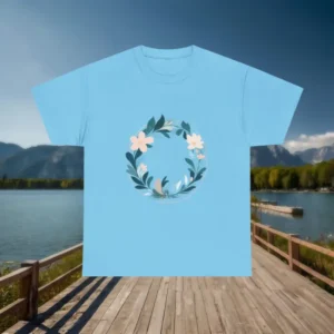 Light blue t-shirt with circular floral wreath graphic, displayed flat on a wooden boardwalk