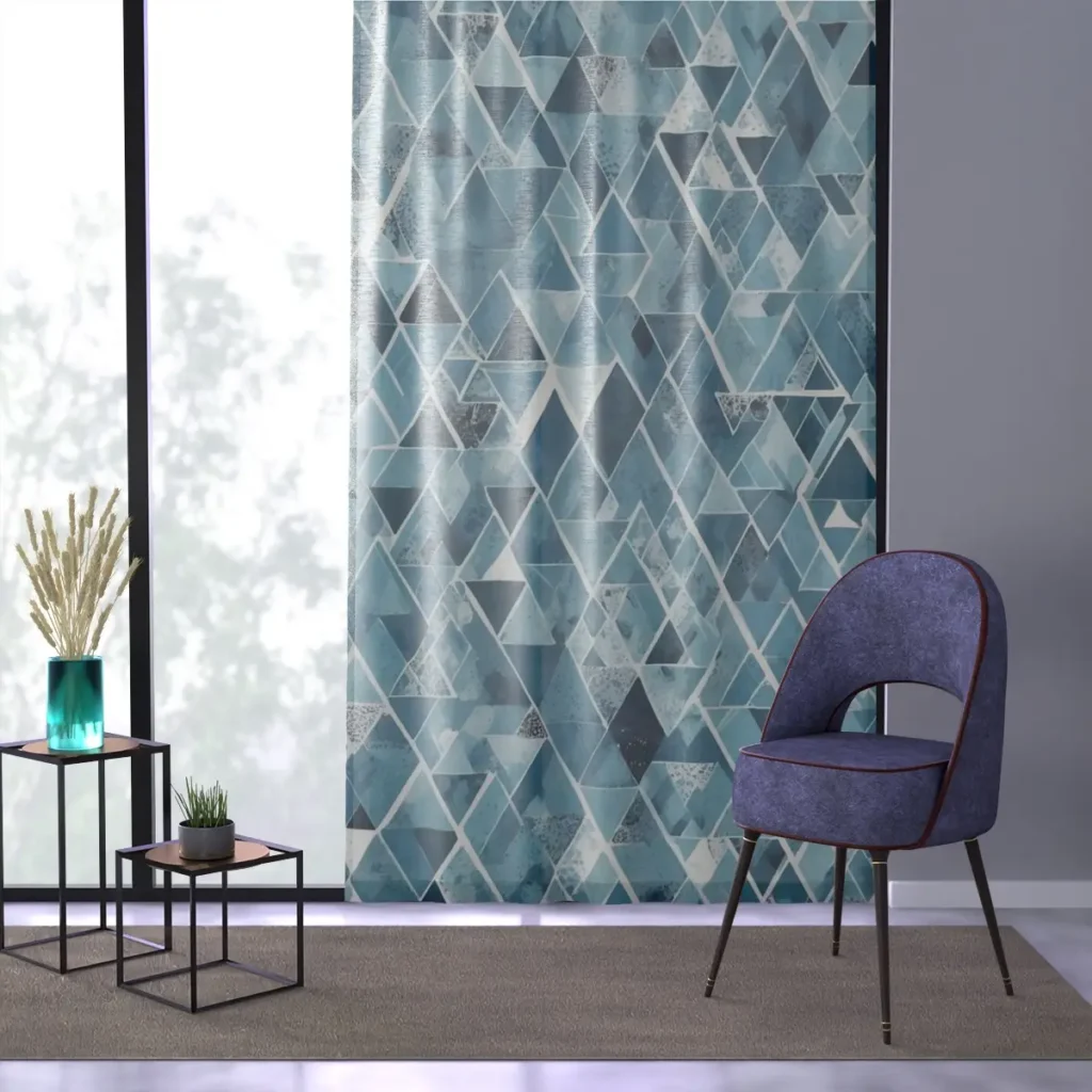 Window curtain with Arctic Angles design featuring an abstract geometric pattern in cool tones, displayed in a modern room setting with a chair and decorative plants.