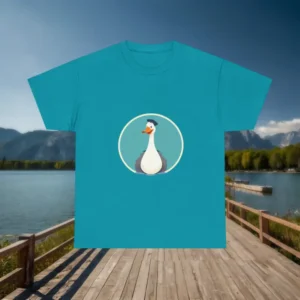 Turquoise t-shirt with a cartoon silly goose illustration displayed flat on a dock with a scenic lake and mountain backdrop